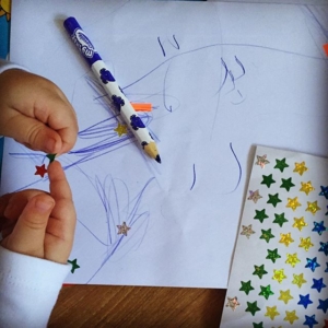 Enjoying stickers & colouring. Super fine motor activity.