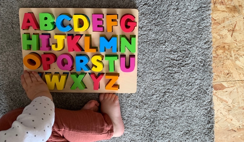 printplaylearn alphabet wooden toy on grey carpet with child 7 Fun Ways to Get Your Child Excited about Literacy