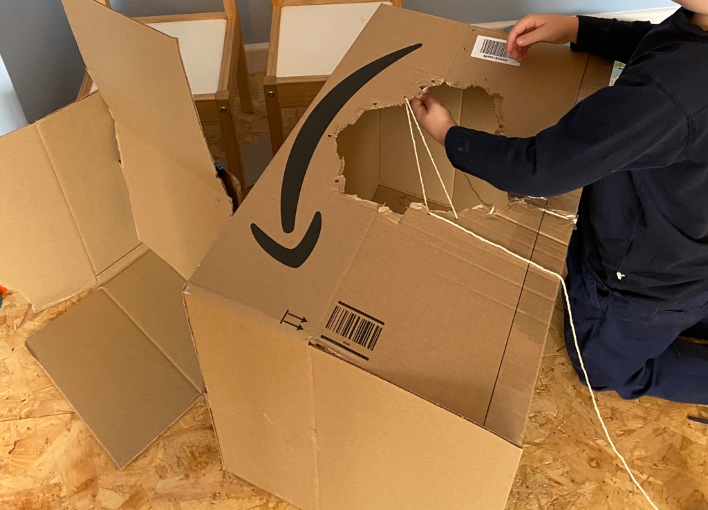 kid playing with a cardboard box on the floor print play learn